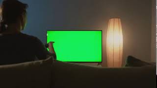 woman is sitting on the couch watching tv with a green screen switching channels with a [upl. by Acimak]