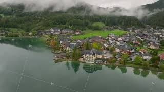 Low clouds are reflecting on the waters of Fuschlsee lake with the Austrian Alps in the background [upl. by Tegdirb]