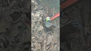 A worker on the bucket of a crawler excavator pulls something out of a rock with the bucket [upl. by Aeresed]