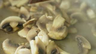 fresh champignon mushrooms stirring with plastic spatula in a frying pan slow motion closeup [upl. by Acenahs]