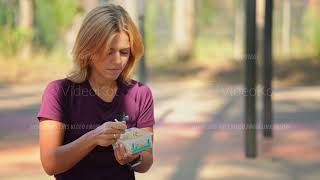 Cheerful Caucasian woman is eating rive from lunchbox sitting at workout area at summer day [upl. by Gniy]