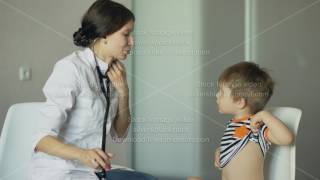 Young woman doctor talking little boy and listening with stethoscope in medical office [upl. by Norved]